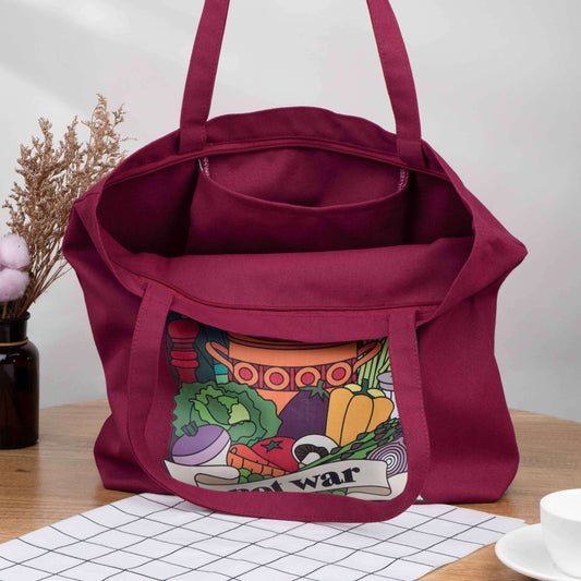 Burgundy tote bag made from canvas with vintage retro style design on the front saying Make Soup Not War, with an illustration of soup ingredients and an old style pot. It has a zip across the top and a pocket inside. Could be a shopping bag or a handbag.