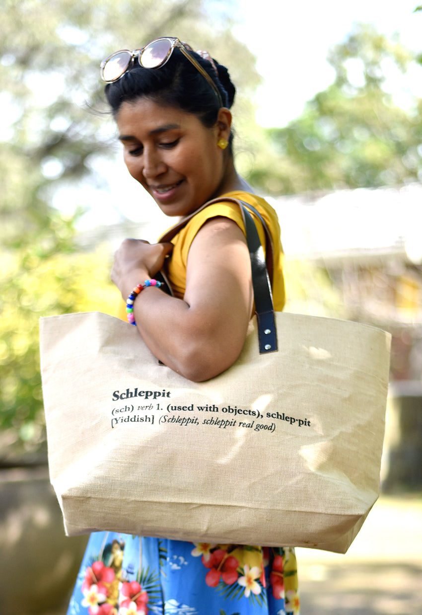 Schlep it, schlep it real good! Need something to schlep your stuff around? This is it. Cooked Concepts' Schleppit (v) Tote is made ethically in India from sustainable Jute, features leather straps and metal rivets and the design is screen printed on the front. 